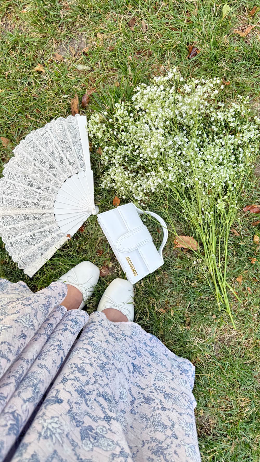 A lace fan and flowers laid out on the grass